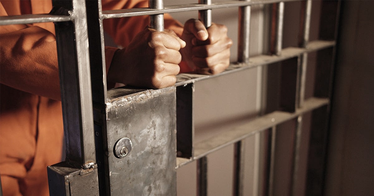 Mans hands between jail bars